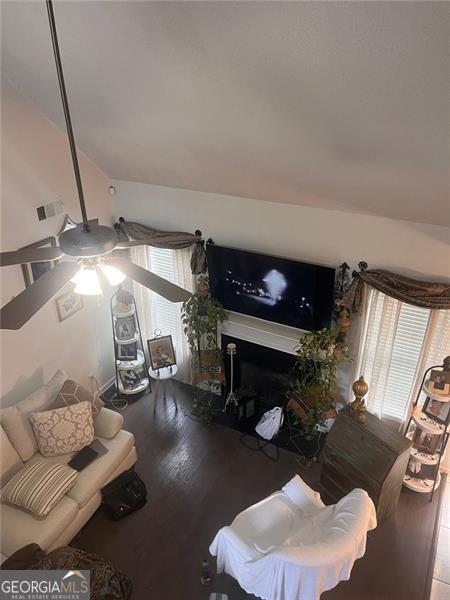 living room with vaulted ceiling, a fireplace, wood finished floors, and visible vents