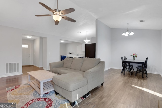 living area with lofted ceiling, baseboards, visible vents, and wood finished floors