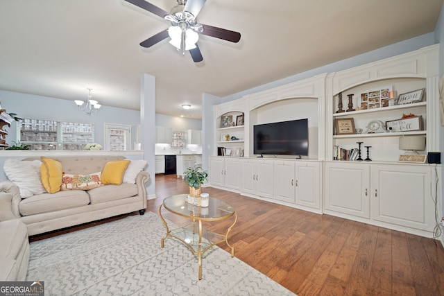 living area with wood finished floors and ceiling fan with notable chandelier