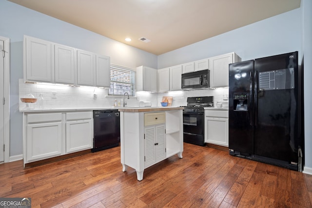 kitchen featuring light countertops, black appliances, and white cabinetry