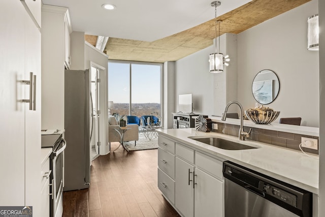 kitchen featuring appliances with stainless steel finishes, pendant lighting, white cabinets, and a sink