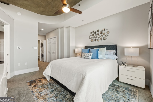 bedroom featuring carpet, stacked washer and dryer, a closet, a ceiling fan, and baseboards