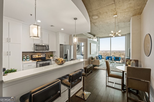 kitchen featuring stainless steel appliances, white cabinetry, hanging light fixtures, light countertops, and dark wood finished floors