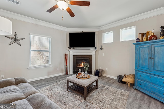 living room featuring ornamental molding, visible vents, baseboards, and wood finished floors