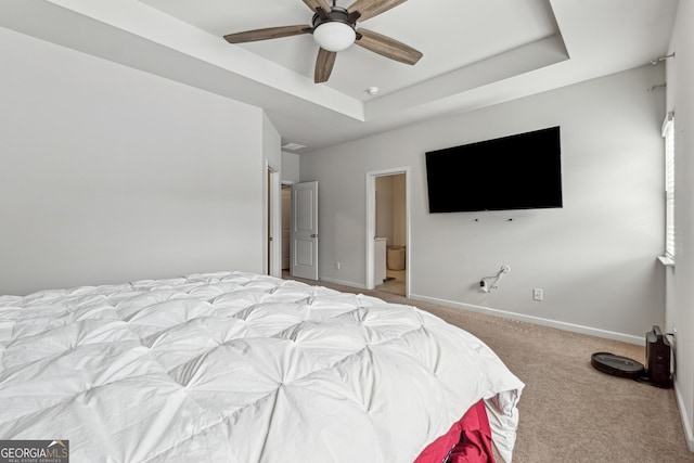 bedroom with a ceiling fan, a raised ceiling, light colored carpet, and baseboards