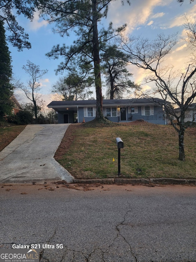 view of front of house with concrete driveway, a carport, and a front lawn