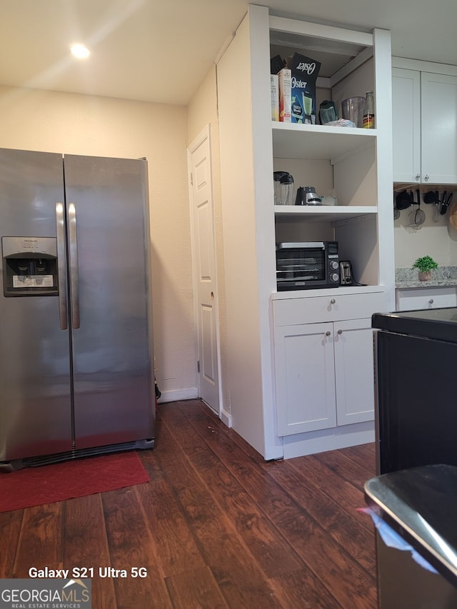 kitchen featuring dark wood-type flooring, stainless steel fridge, and white cabinetry