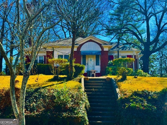 view of front of property featuring stairs and brick siding