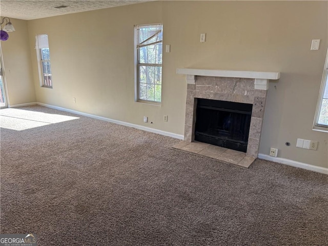 unfurnished living room with a textured ceiling, a fireplace, baseboards, and light colored carpet