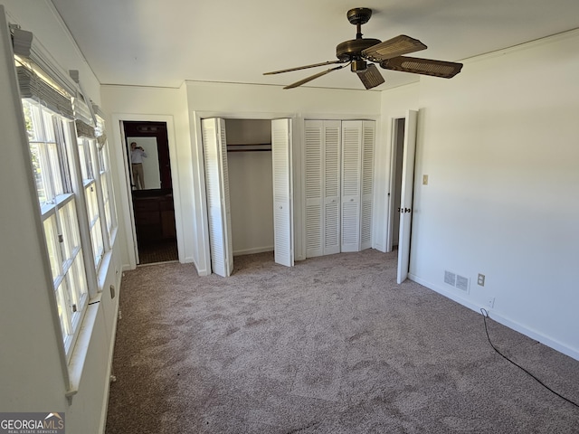 unfurnished bedroom with multiple closets, visible vents, carpet flooring, ceiling fan, and baseboards