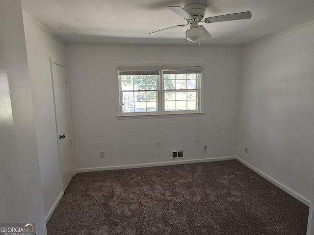 unfurnished room with crown molding, dark colored carpet, visible vents, ceiling fan, and baseboards