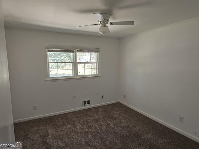 empty room featuring dark colored carpet, visible vents, ornamental molding, ceiling fan, and baseboards