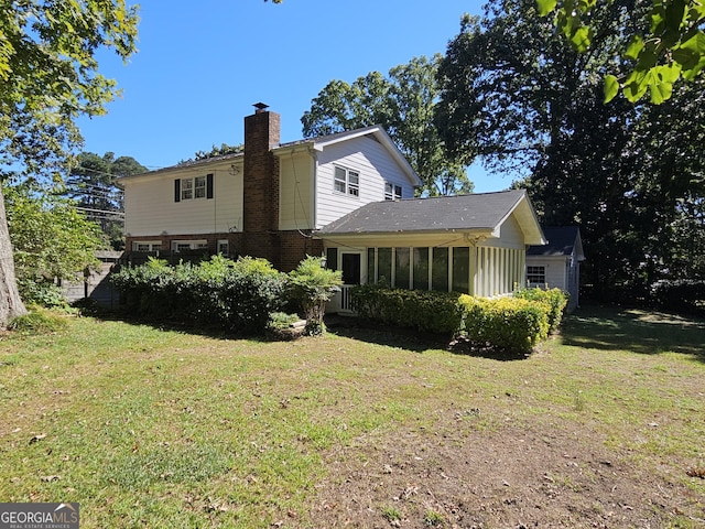 back of house with a yard, a chimney, and a sunroom