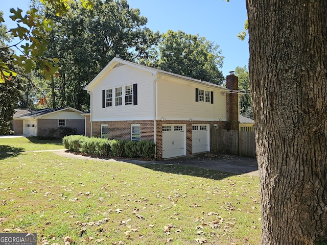 exterior space featuring brick siding, a yard, a chimney, a garage, and driveway