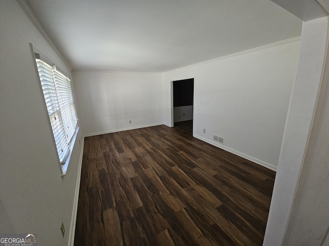 empty room featuring ornamental molding, dark wood-style flooring, visible vents, and baseboards