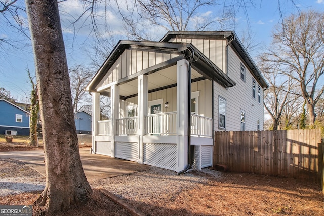 view of side of property featuring covered porch, fence, and board and batten siding