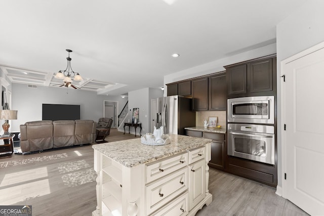 kitchen with light wood finished floors, appliances with stainless steel finishes, dark brown cabinetry, light stone countertops, and coffered ceiling