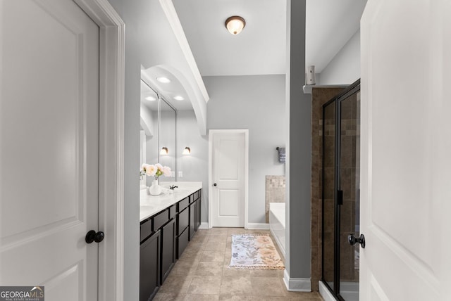 bathroom featuring a garden tub, double vanity, a shower stall, baseboards, and tile patterned floors