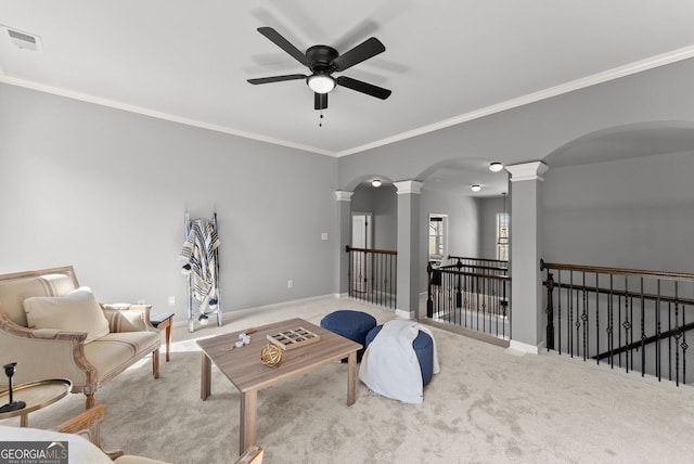 carpeted living area with arched walkways, visible vents, baseboards, decorative columns, and crown molding