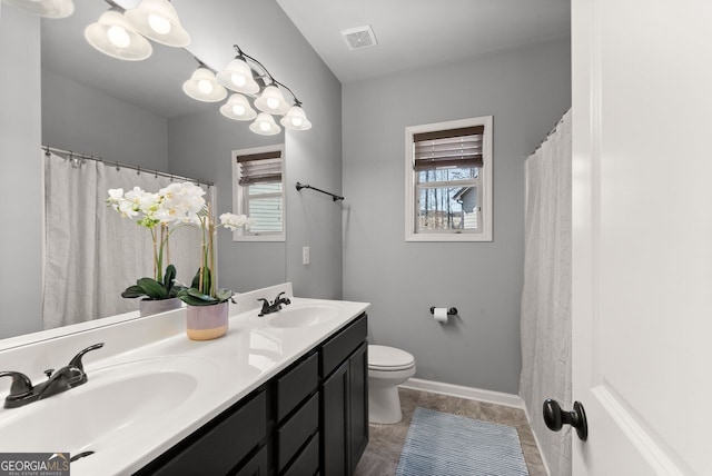 bathroom featuring toilet, double vanity, visible vents, and a sink