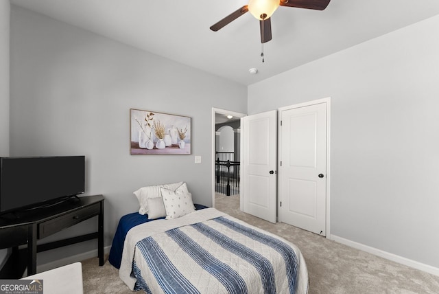 carpeted bedroom featuring a ceiling fan, arched walkways, and baseboards