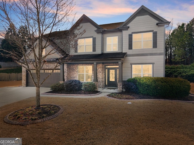 view of front of house with a garage, driveway, a yard, and brick siding