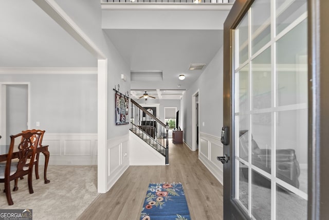 entryway featuring wood finished floors, visible vents, a decorative wall, and stairs