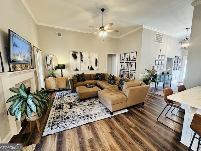 living area featuring dark wood-style floors, visible vents, ceiling fan with notable chandelier, and crown molding