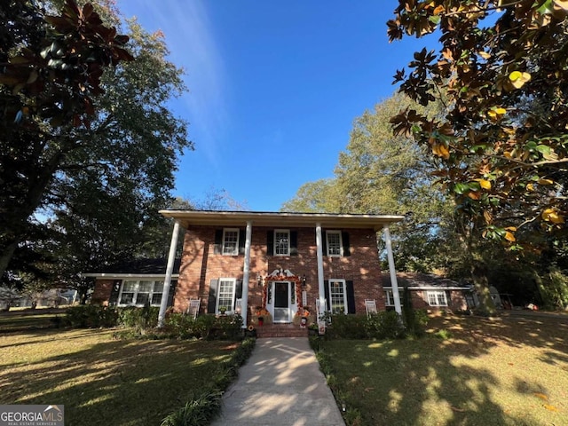 greek revival house featuring brick siding and a front yard