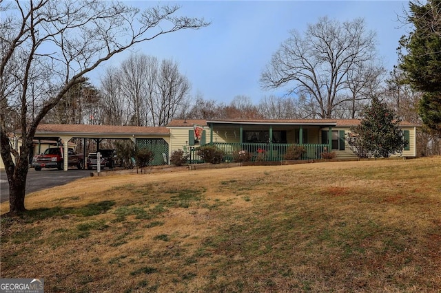 single story home featuring a carport, a porch, and a front lawn