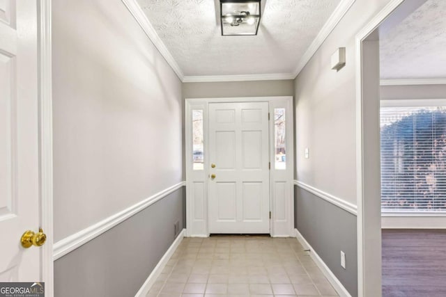 entryway with ornamental molding, a textured ceiling, and baseboards