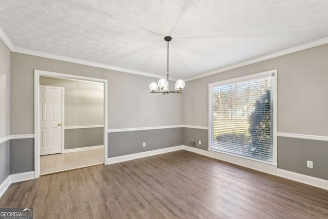 unfurnished dining area with baseboards, wood finished floors, crown molding, a textured ceiling, and a notable chandelier