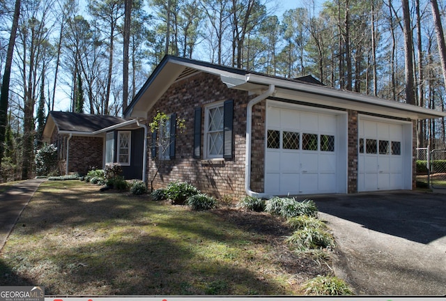 view of property exterior with aphalt driveway, brick siding, and a garage