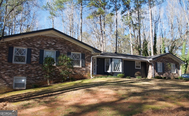 ranch-style home with brick siding, board and batten siding, and a front yard