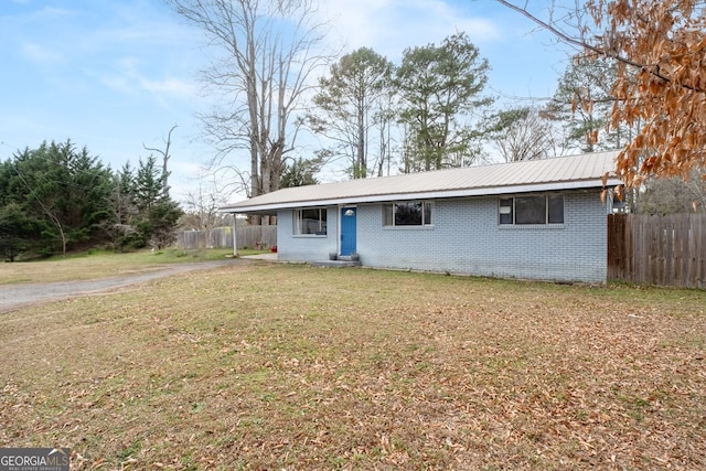 view of front of house with metal roof, brick siding, a front lawn, and fence