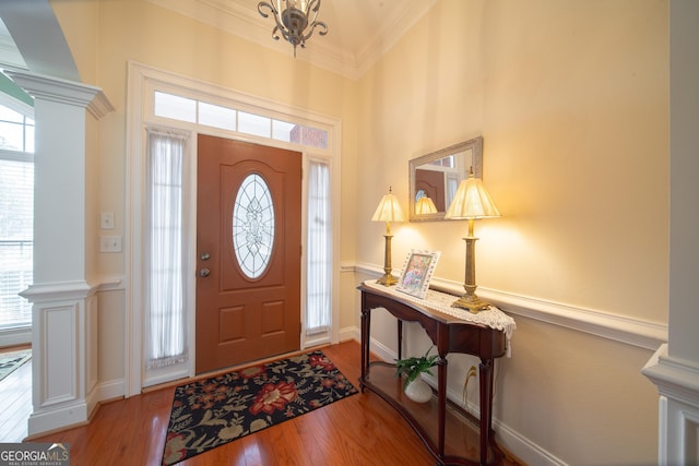 foyer entrance with a wainscoted wall, ornamental molding, light wood-type flooring, and decorative columns