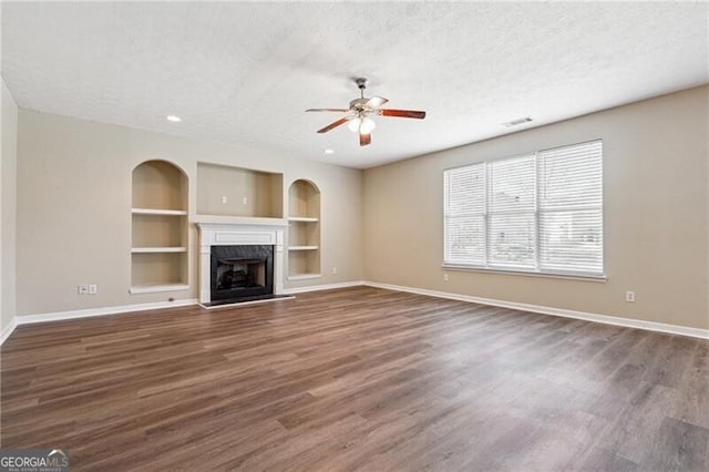 unfurnished living room featuring baseboards, a textured ceiling, ceiling fan, and built in features