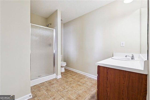 bathroom with toilet, baseboards, a shower stall, and vanity