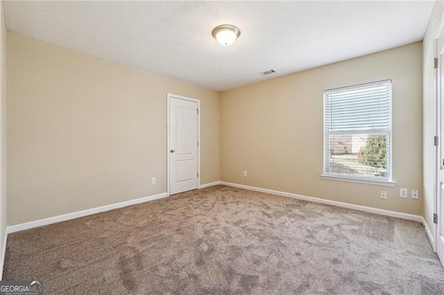 carpeted spare room with baseboards and visible vents