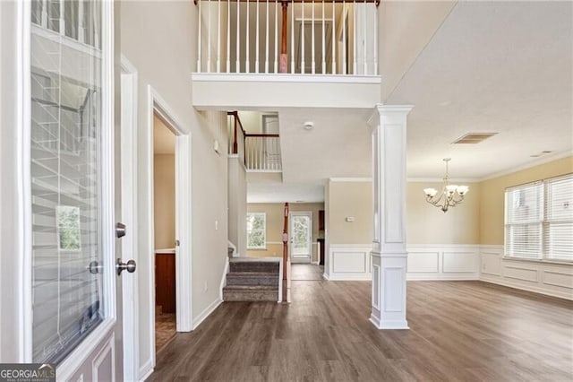 entryway featuring dark wood-style flooring, visible vents, stairs, ornamental molding, and ornate columns