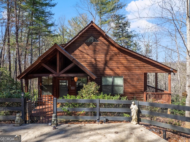 rustic home featuring a fenced front yard and a gate