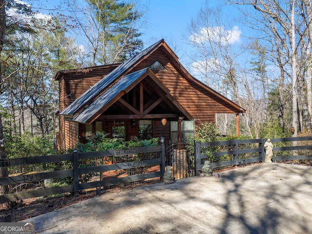 chalet / cabin featuring a fenced front yard and log veneer siding