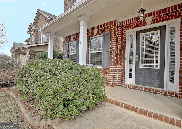 property entrance with covered porch and brick siding