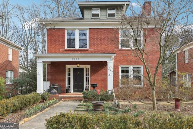 american foursquare style home featuring a chimney and brick siding