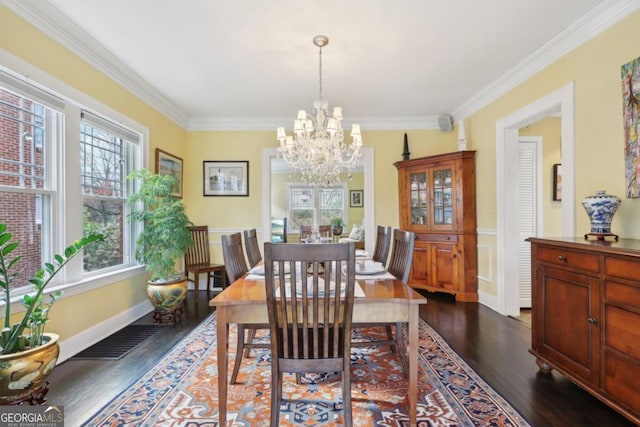 dining area featuring baseboards, visible vents, dark wood finished floors, ornamental molding, and an inviting chandelier