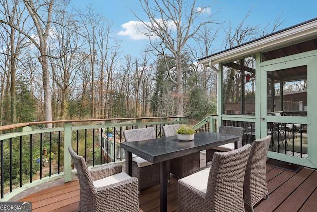 deck with a sunroom and outdoor dining area