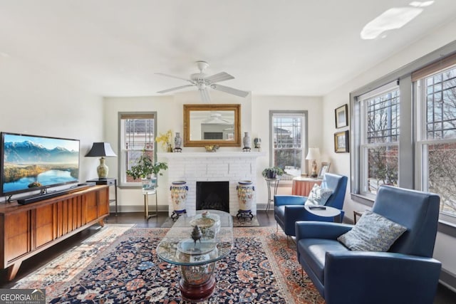 living area featuring dark wood-style floors, a fireplace, baseboards, and ceiling fan