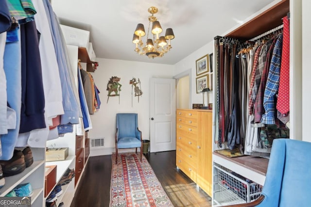 spacious closet with visible vents, dark wood-type flooring, and a notable chandelier