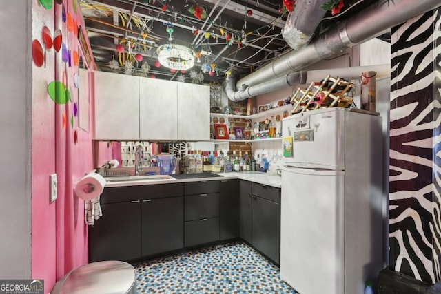 kitchen featuring freestanding refrigerator, light countertops, a sink, and light floors