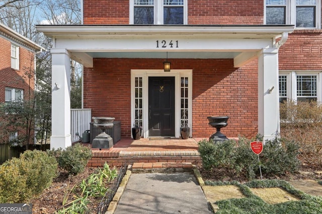 entrance to property with covered porch and brick siding